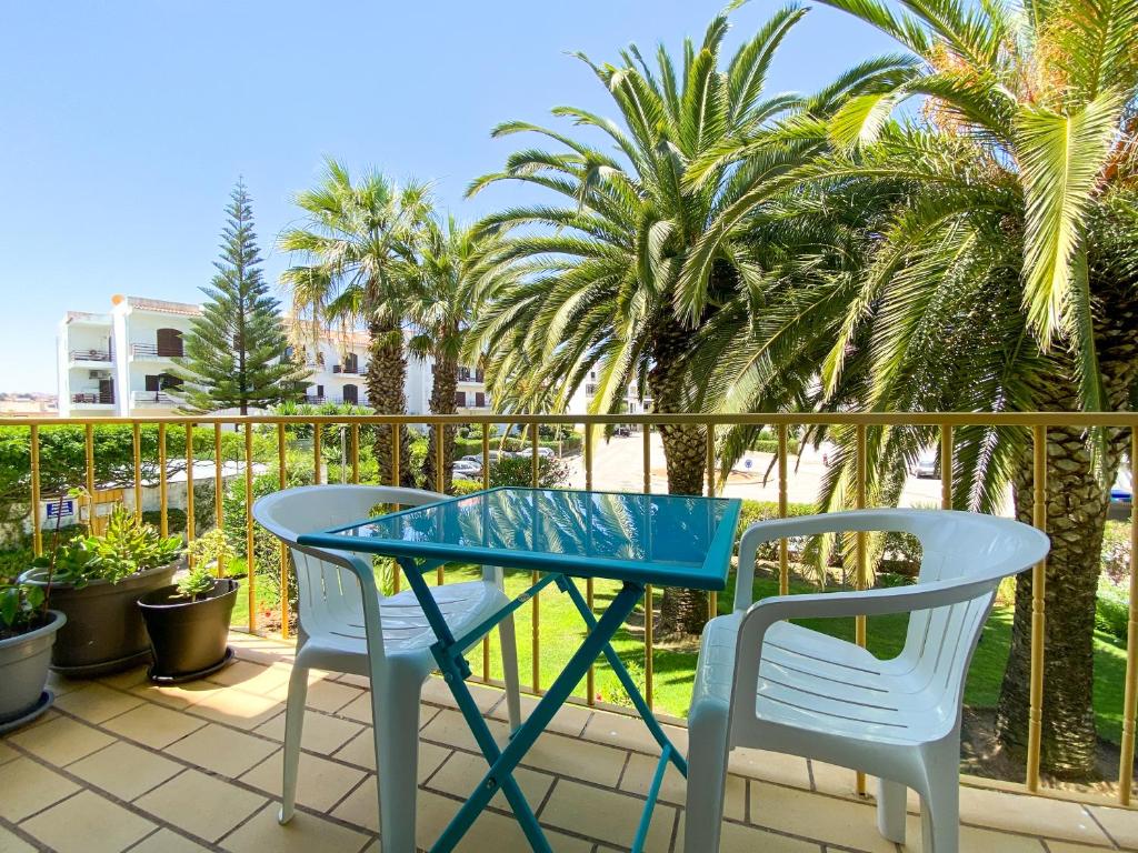 ラゴスにあるCasa Moinho - Apartamento com piscinaのヤシの木が茂るバルコニー(テーブル、椅子2脚付)