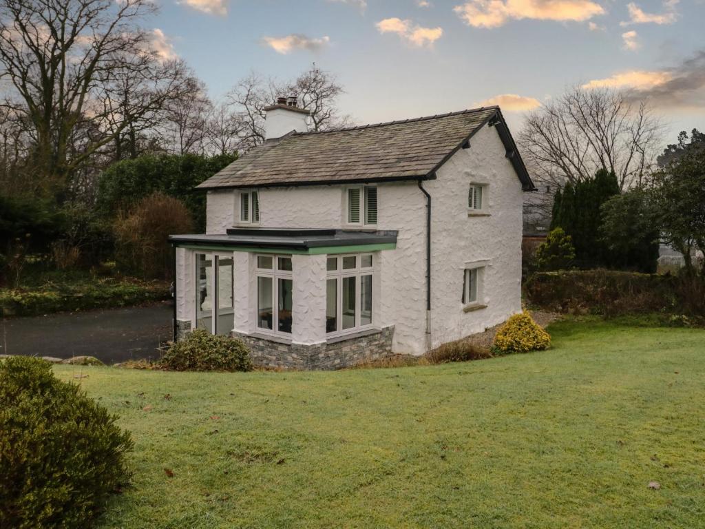a white house sitting on top of a lush green field at Green Stile Cottage in Windermere