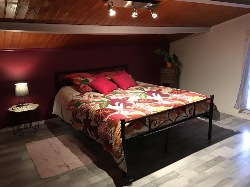ein Schlafzimmer mit einem großen Bett mit roten Kissen in der Unterkunft Le Welcome in Coutras