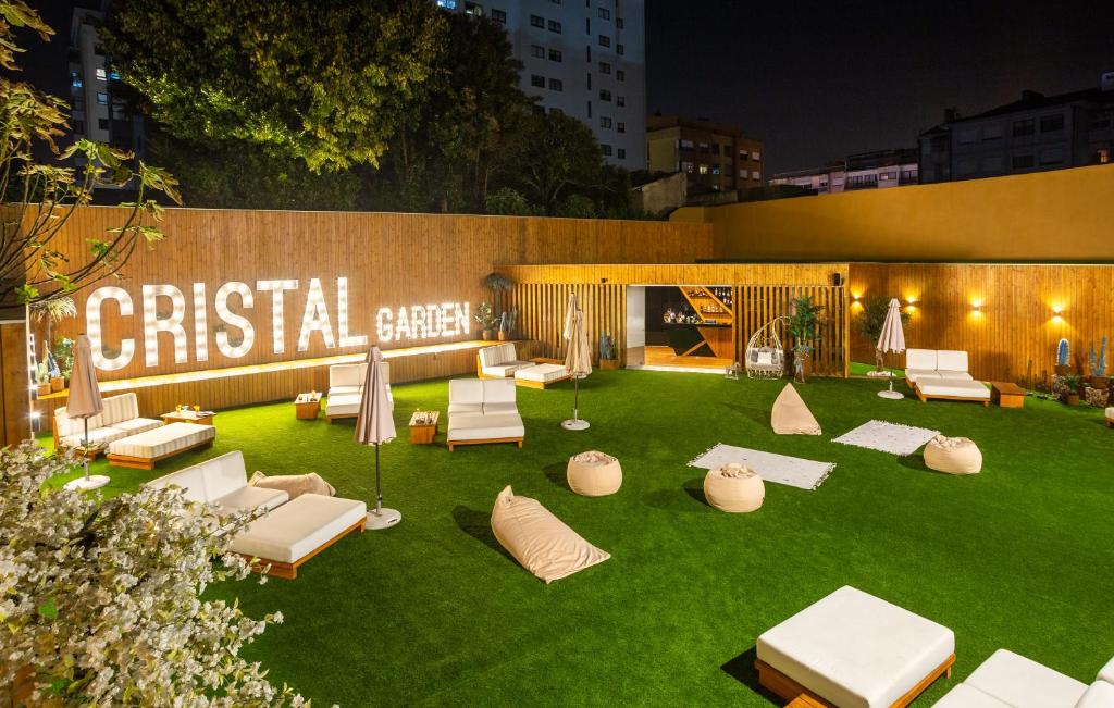 einen Garten mit weißen Stühlen und Sonnenschirmen auf dem Rasen in der Unterkunft Hotel Cristal Porto in Porto