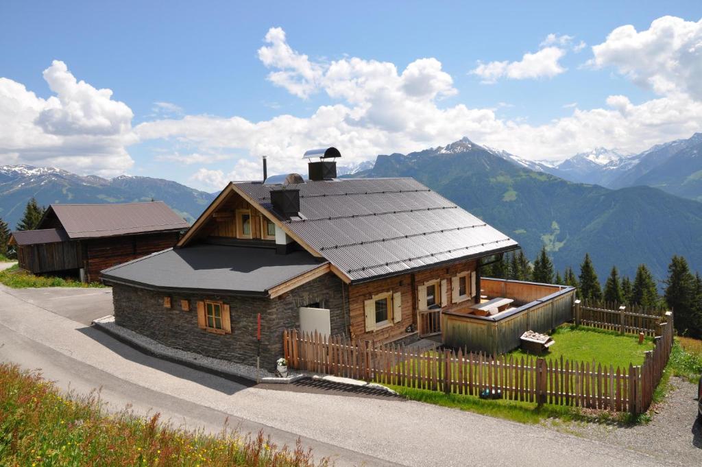 a small wooden house with a fence and mountains at Berghütte Ahornblick in Hippach