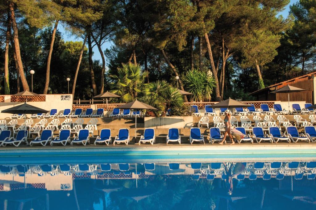 uma piscina com cadeiras, guarda-sóis e árvores em Belambra Clubs La Colle-sur-Loup - Les Terrasses De Saint-Paul De Vence em La Colle-sur-Loup