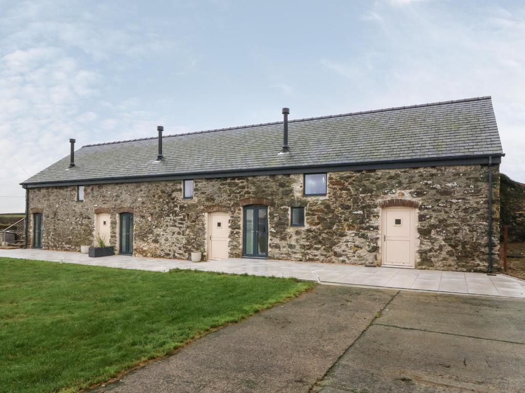 an old stone building with a garage at Beudy in Gwalchmai