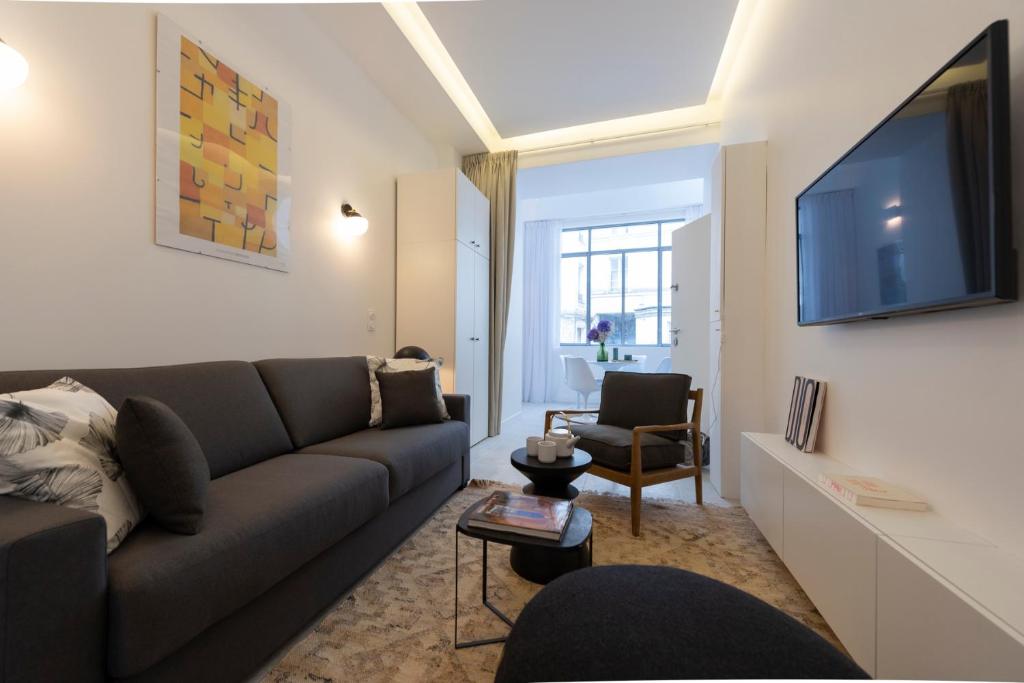 ein Wohnzimmer mit einem Sofa und einem Flachbild-TV in der Unterkunft Mayenne in Paris
