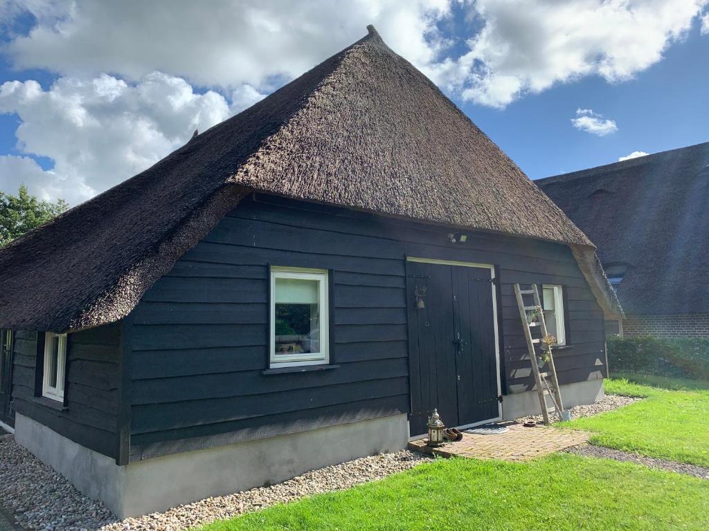 una cabaña negra con techo de paja en De Stal - Buitenplaats Ruitenveen, privé!, en Nieuwleusen