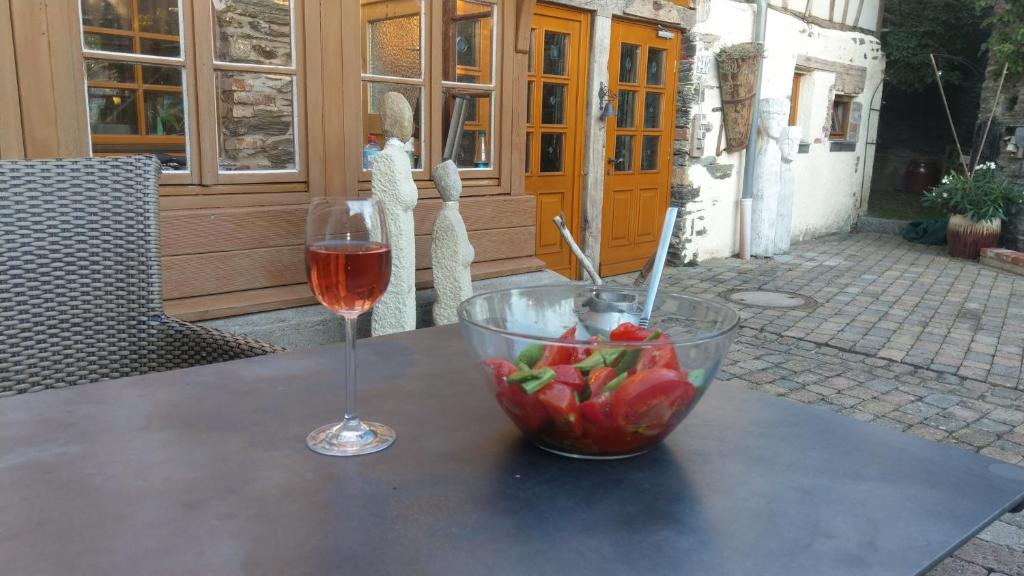 a glass of wine and a bowl of fruit on a table at Ferienwohnung Kunstscheune Mosel in Raversbeuren