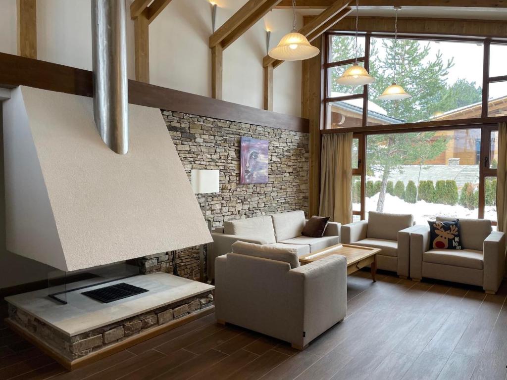 uma sala de estar com sofás e uma lareira em Villa Tama Pirin Golf and Spa em Bansko