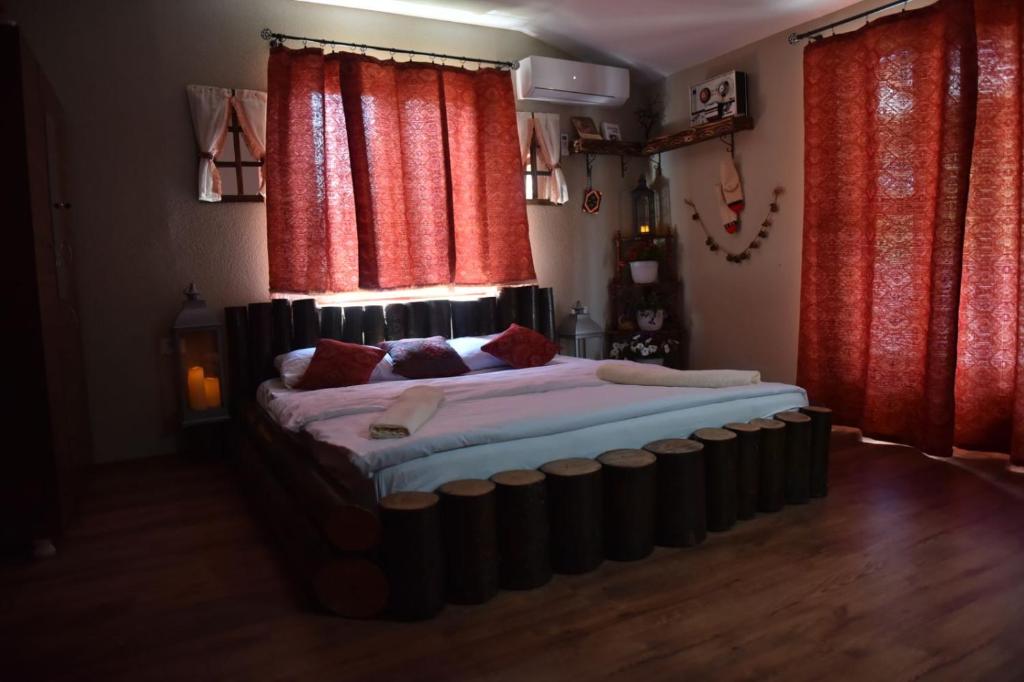 Cama grande en habitación con cortinas rojas en HANI I VJETER Boutique Hotel, en Prizren