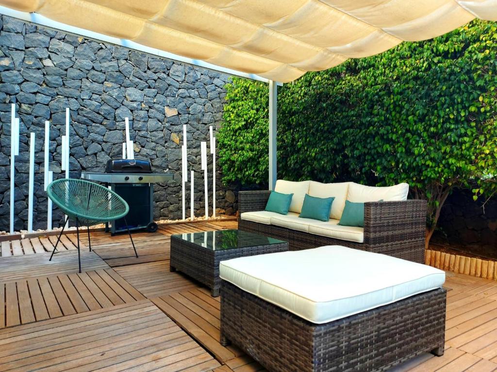 um pátio com um sofá, uma mesa e comodidades para churrascos em Duplex with sea views, garden and terrace em Santa Cruz de Tenerife
