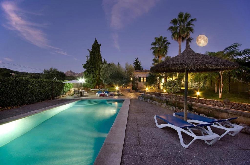 una piscina con 2 tumbonas y una sombrilla en Sunset Villa Es Pujolet, en Alcudia
