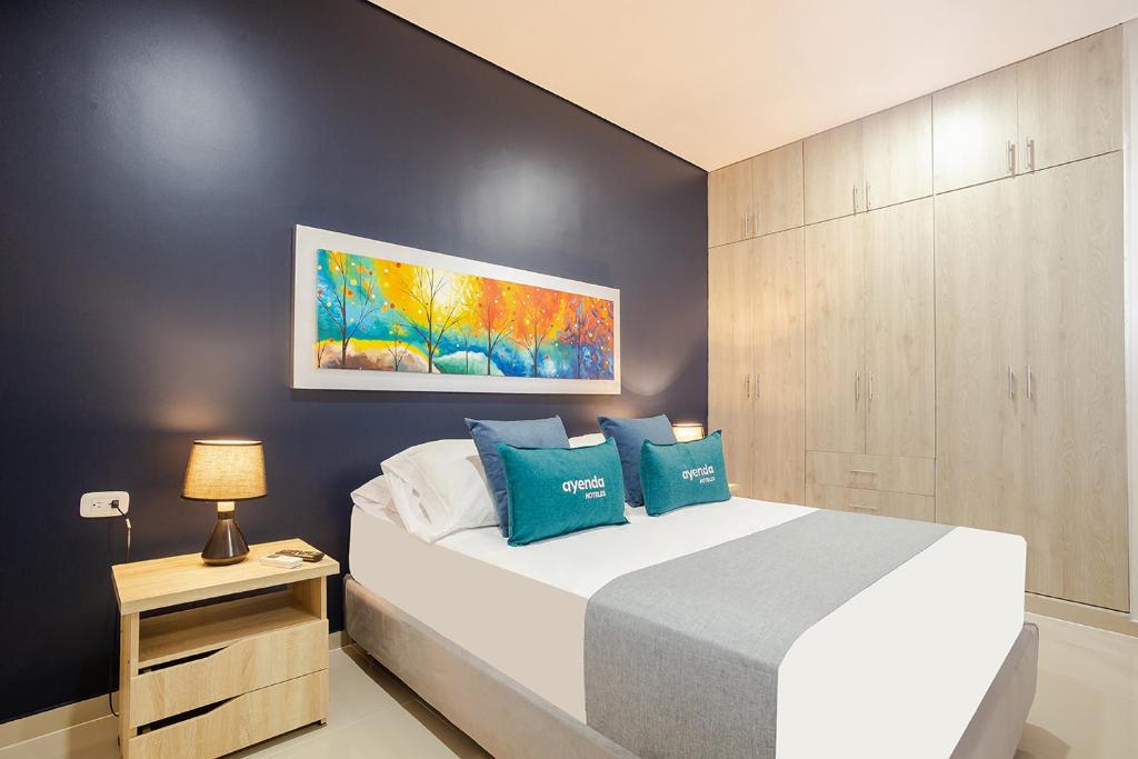 1 dormitorio con 1 cama blanca grande con almohadas azules en Ayenda Montepinares en Montería