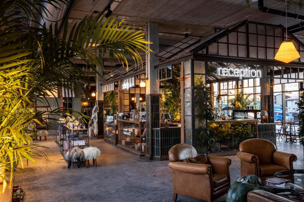 a lobby with chairs and tables and plants at The Greenhouse Hotel in Hveragerði