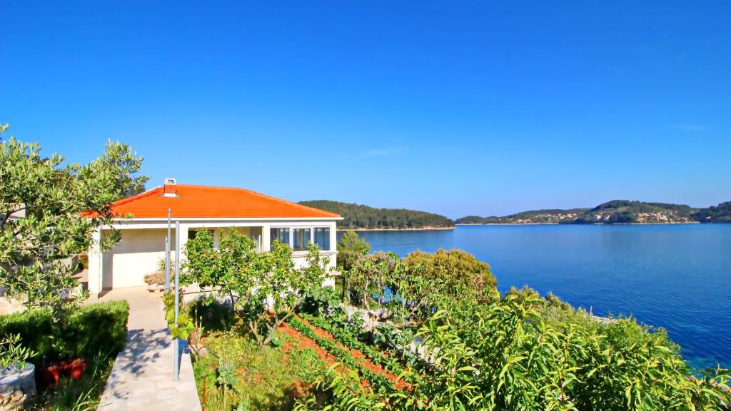 ein Haus mit einem orangenen Dach neben einem See in der Unterkunft Vacation House Katica in Vela Luka