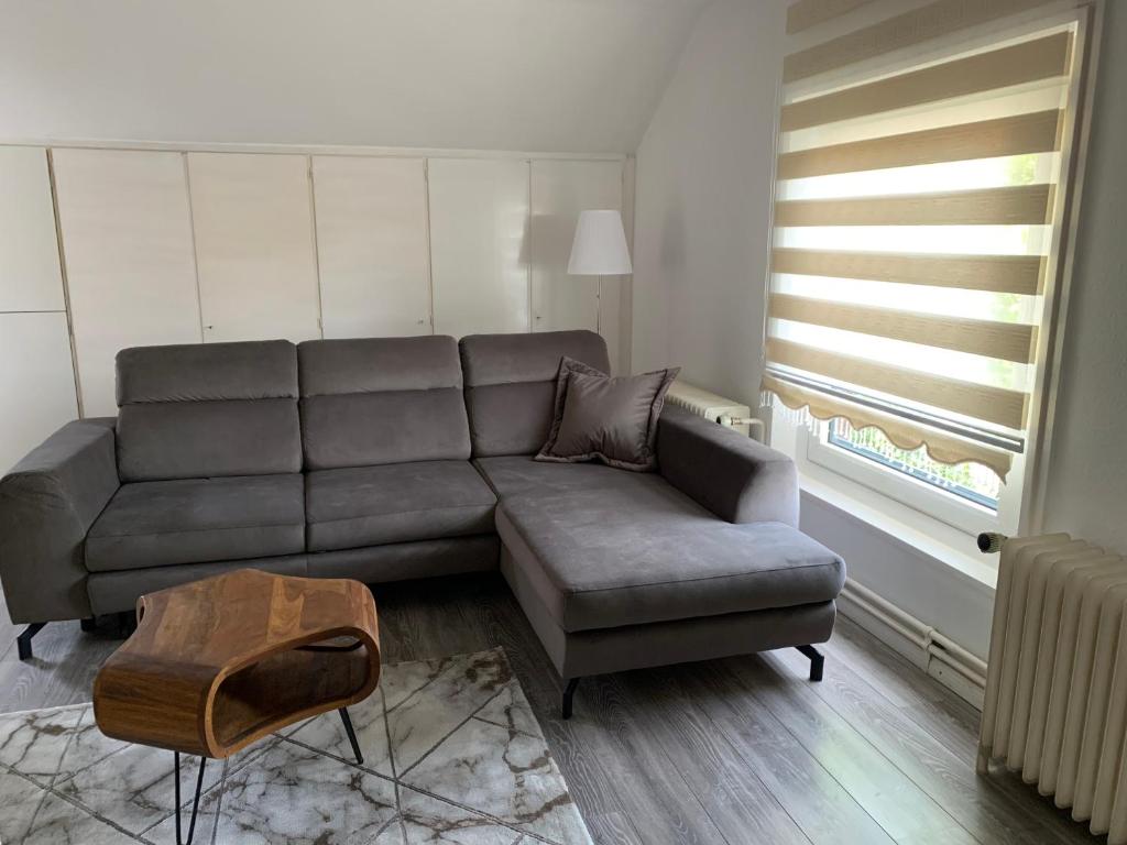 a living room with a gray couch and a table at Gemütliche Ferienwohnung bei Hamburg in Reinbek