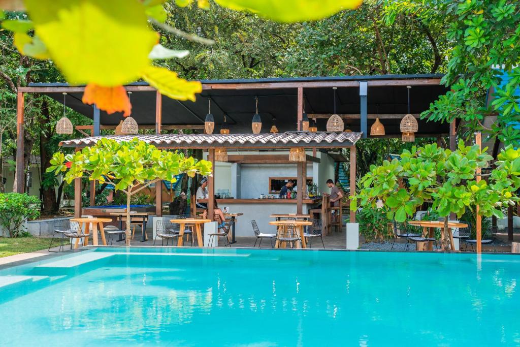 uma piscina em frente a um restaurante com mesas e cadeiras em Selina River Venao em Playa Venao