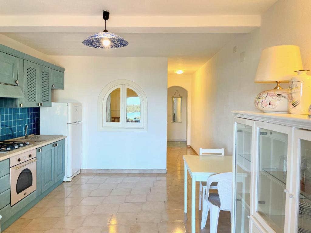 a kitchen with blue cabinets and a table with a tableablish at Casa Leo - Villaggio Baia De Bahas in Golfo Aranci