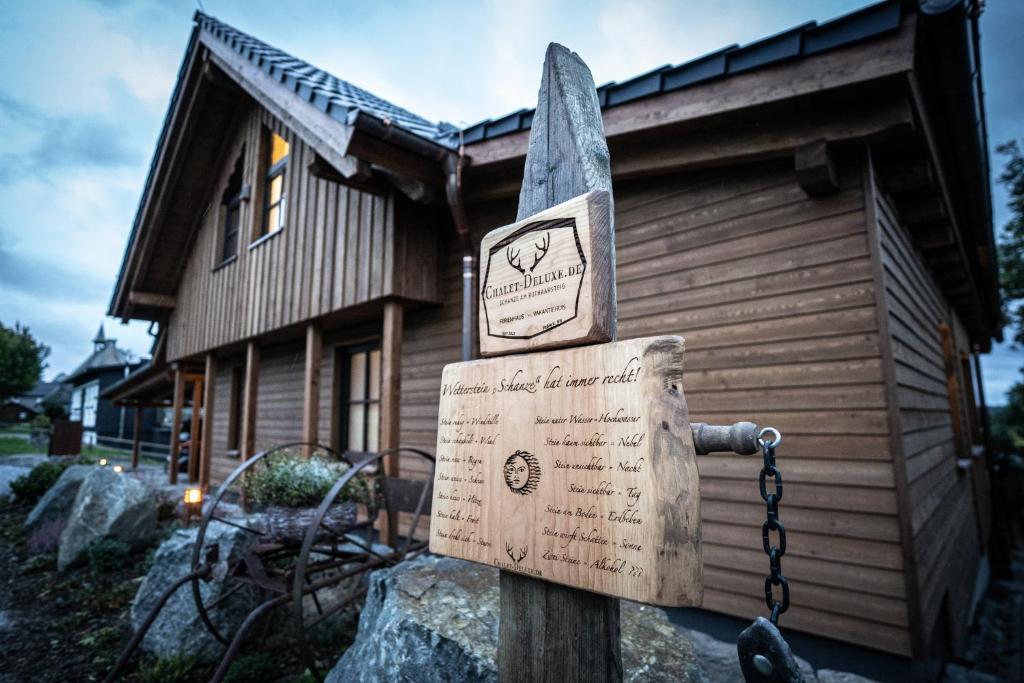 un panneau en bois devant une maison dans l'établissement Chalet Deluxe - Das Premium Ferienhaus im Sauerland, à Schmallenberg