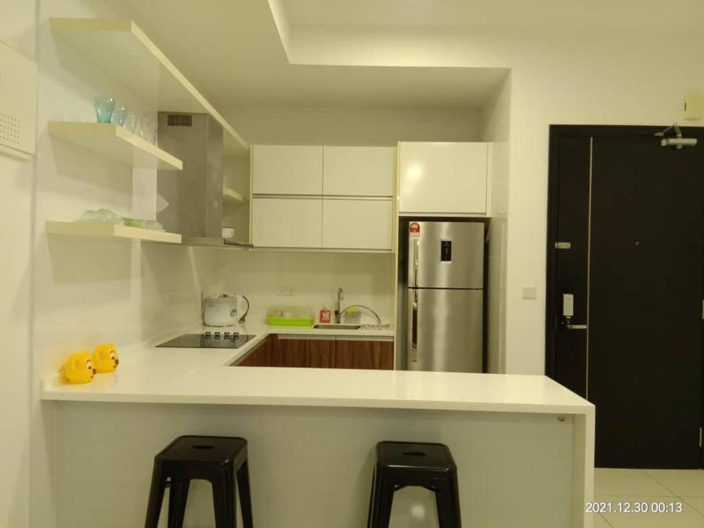 a kitchen with a counter and a refrigerator and stools at Setia Sky 88 Living in the Skies in Johor Bahru