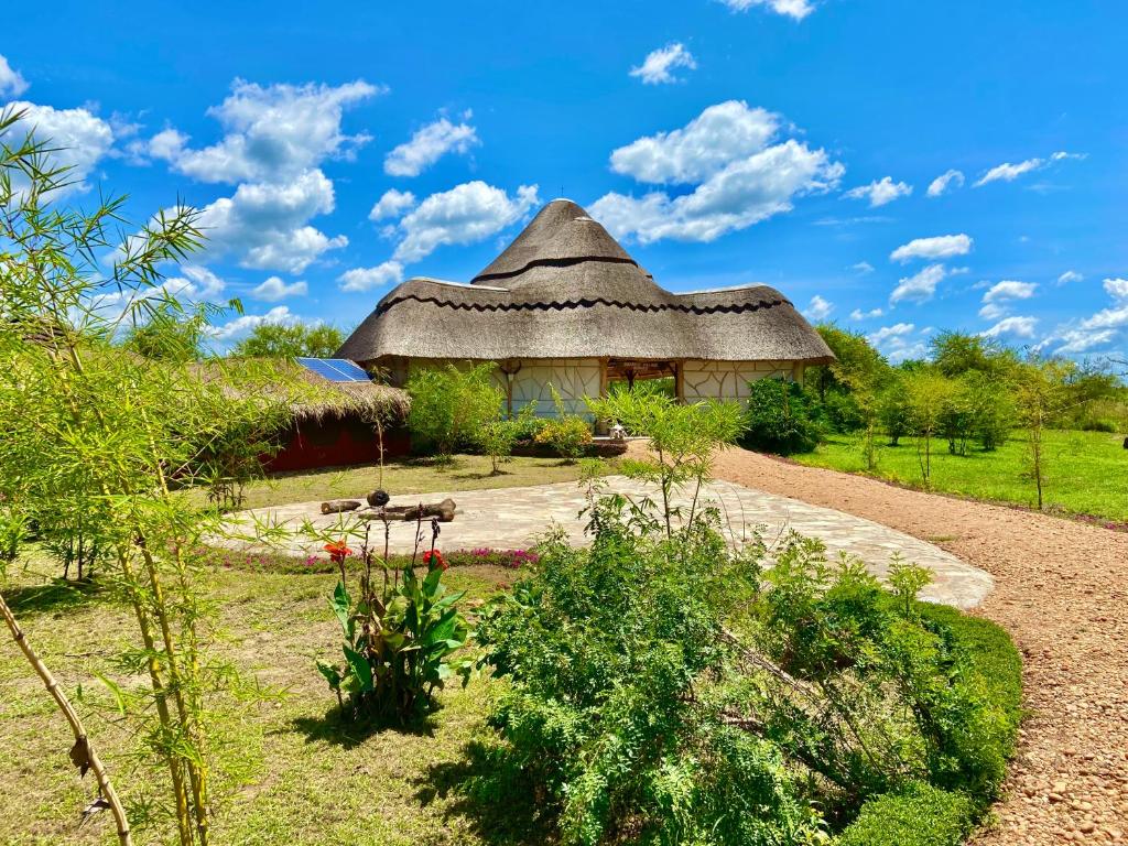 a hut with a thatched roof in a garden at Murchison Falls Bamboo Village in Murchison Falls National Park