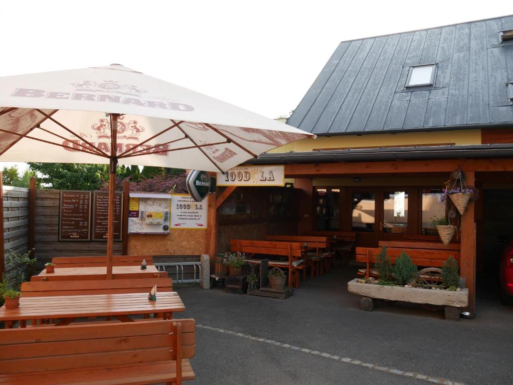a restaurant with wooden benches and an umbrella at 100dola in Malé Hoštice