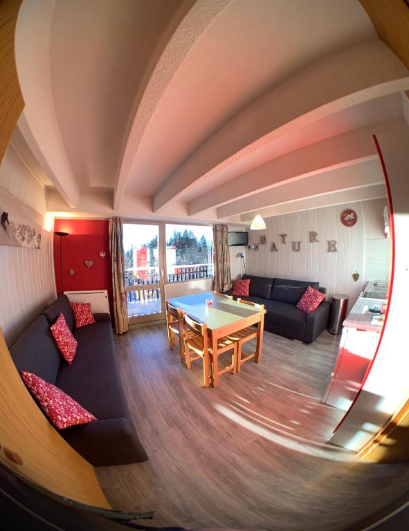 a living room with a table and a couch at Location appartement Chamrousse 1650 - Superbe vue in Chamrousse