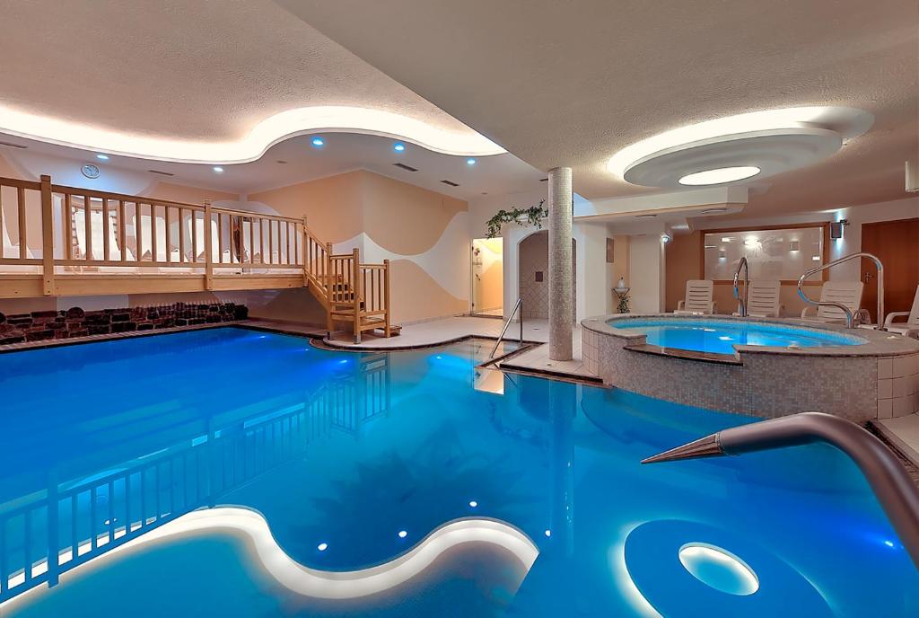 a large pool in a hotel with two jacuzzis at Hotel Negritella in Folgarida