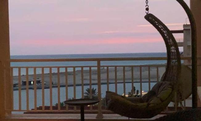 uma rede de descanso numa varanda com vista para o oceano em أزهار الكرز "سويت ملكي مطل على البحر" em King Abdullah Economic City