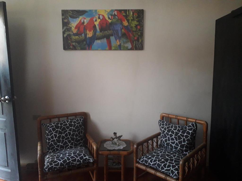 2 sillas en una habitación con una foto en la pared en hospedaje Maluli suit 2, en Santa Elena