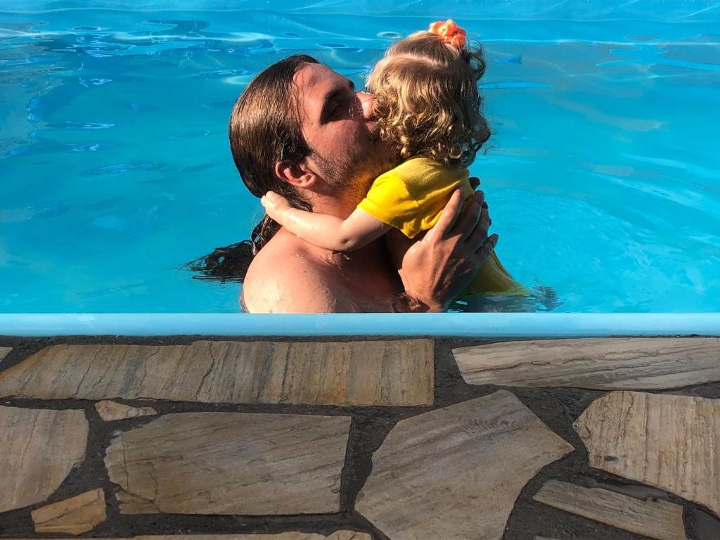 een man die een klein meisje vasthoudt in een zwembad bij Sítio Casa de Campo com piscina Juatuba MG in Juatuba