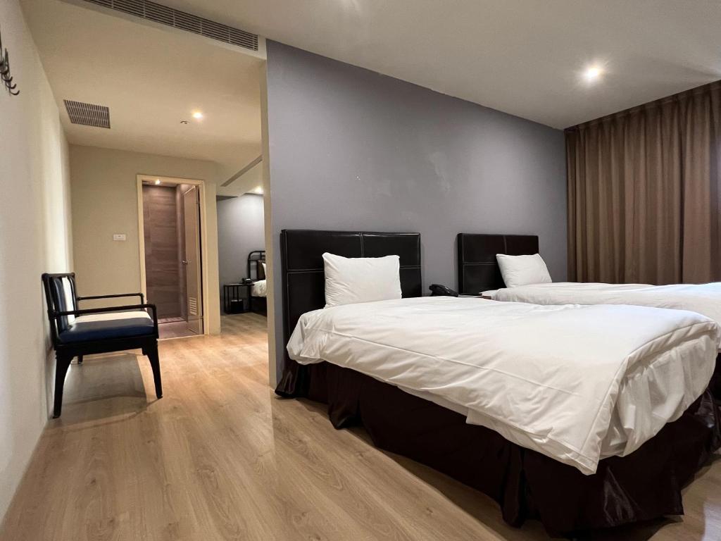 a bedroom with two beds and a chair at Saint Hostel in Beigang