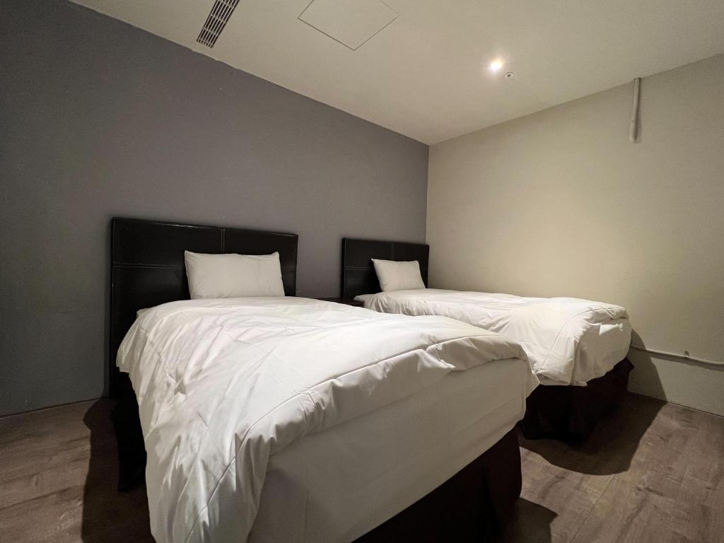 two beds in a room with white sheets and pillows at Saint Hostel in Beigang