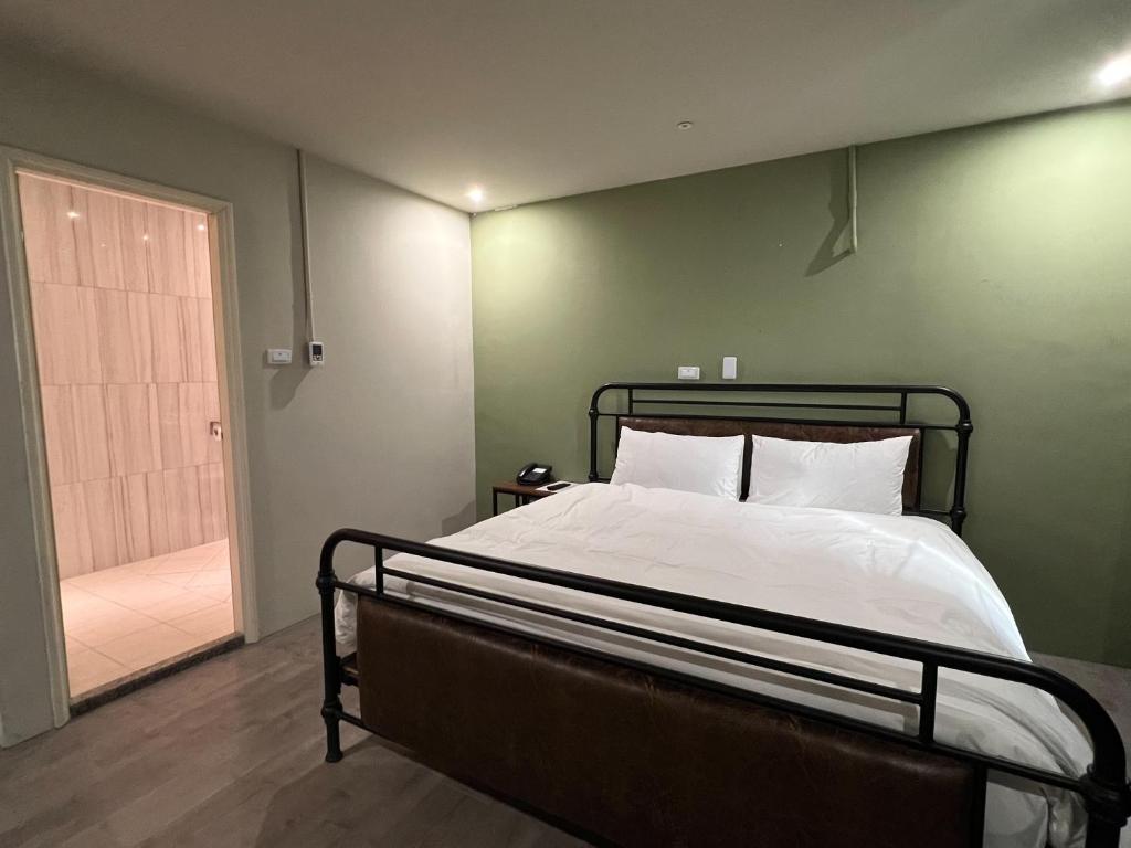 a bedroom with a bed with a green wall at Saint Hostel in Beigang