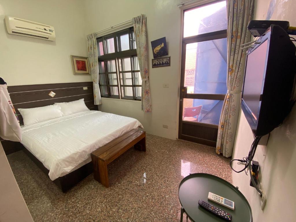 sypialnia z łóżkiem, telewizorem i oknem w obiekcie Danke Hostel w mieście Xiao Liuqiu
