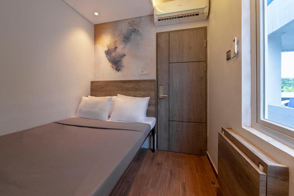 a small room with a bed and a window at Livinn Juanda Airport Surabaya in Sidoarjo