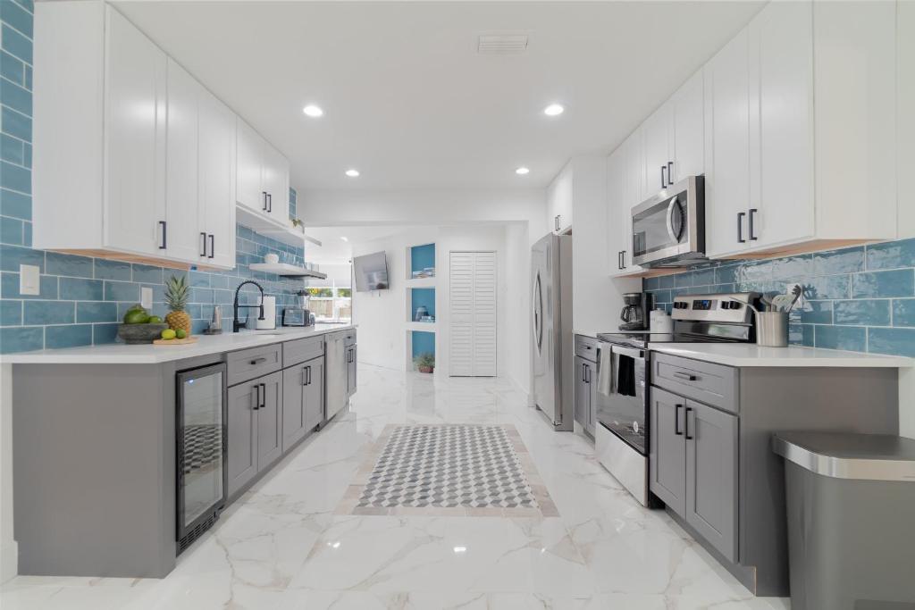 a kitchen with white cabinets and blue tiles at Elegant 5BR West Palm Beach Home Near Beach in West Palm Beach