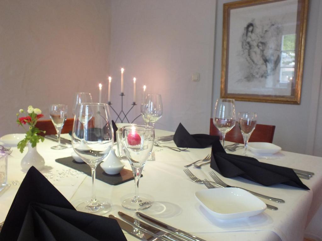 uma mesa de jantar com copos de vinho e velas em Rezas Restaurant Gästehaus em Oberbillig