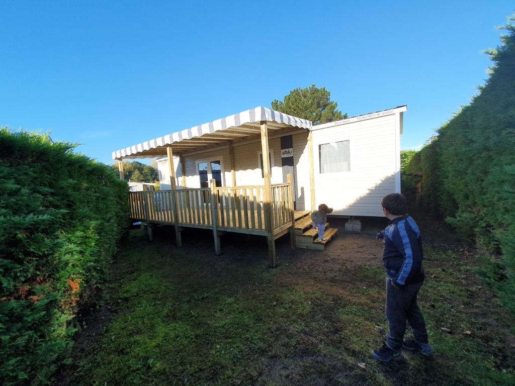 dos niños parados frente a una casa pequeña en Mobil Home 2022 les charmettes 3 Chambres 40m2 en Les Mathes