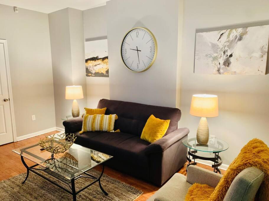 a living room with a couch and a clock on the wall at Upscale 2BD/1.5BA townhome mins to JHH & downtown in Baltimore