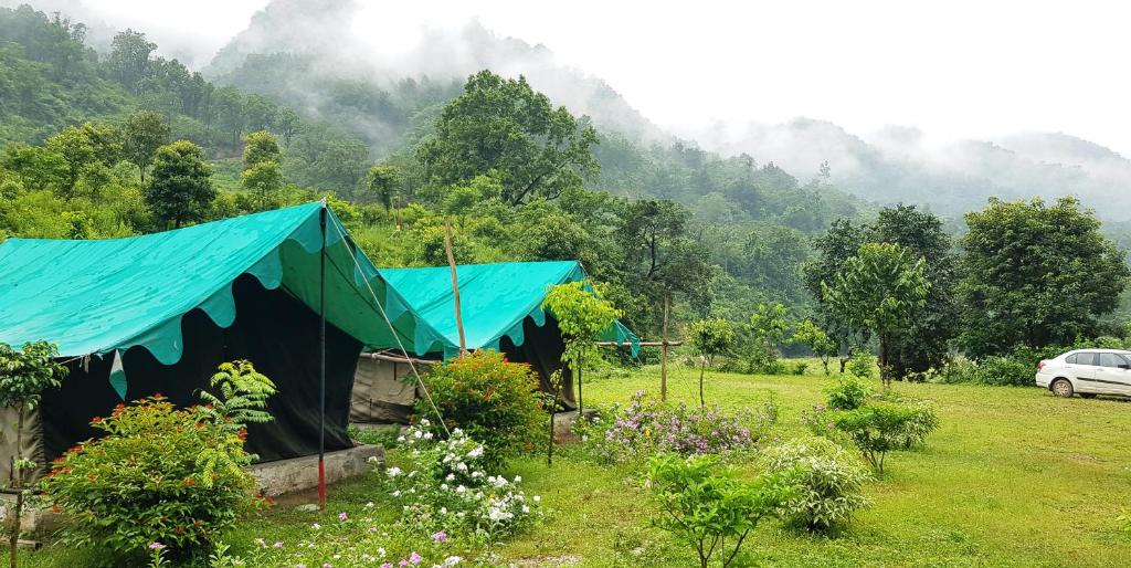 a tent in a field with a car in the background at The Raajas - Camp & Resorts in Rishīkesh