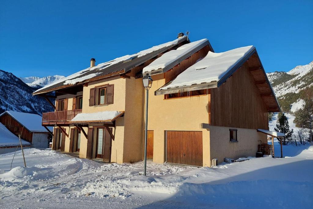 a house is covered in snow in the mountains at Le Vallon des âmes - Large house for 15 people in Roubion in Névache