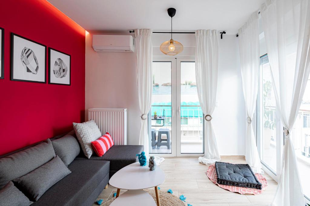 salon z kanapą i czerwoną ścianą w obiekcie Aphrodite Apartment w Atenach