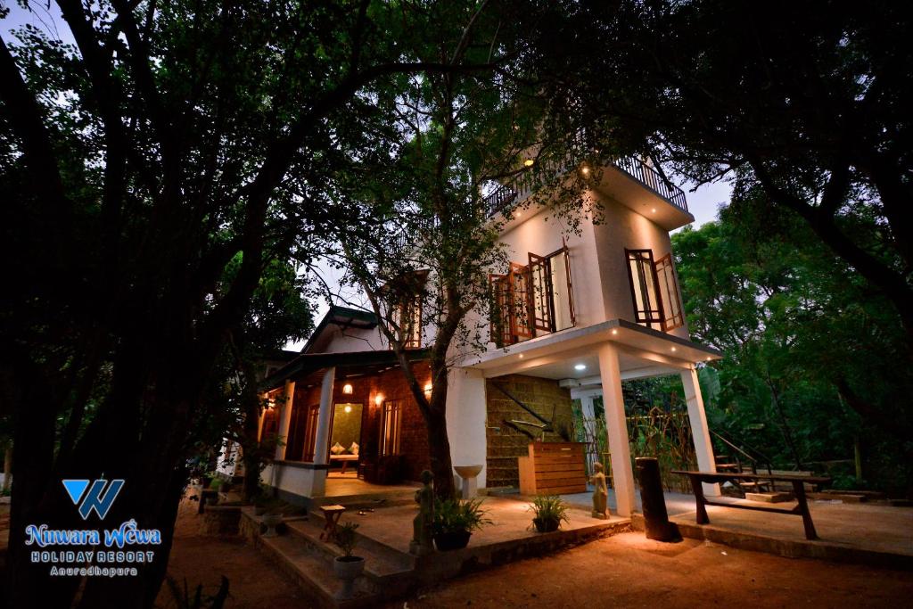 una pequeña casa blanca con un árbol delante en Nuwara Wewa Holiday Resort en Anuradhapura