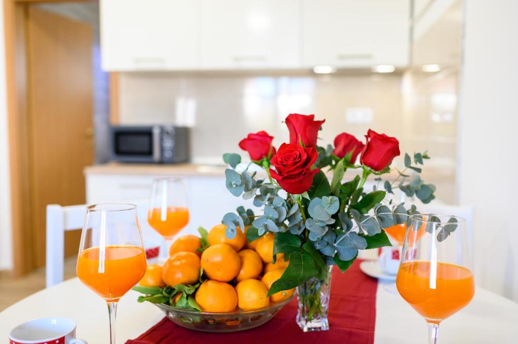un vase de roses et d'oranges sur une table avec du jus d'orange dans l'établissement APARTMAN ANA, METKOVIĆ, à Metković
