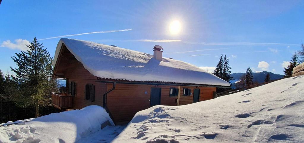 a house covered in snow with the sun behind it at Bergzeit Klippitz in Klippitztorl