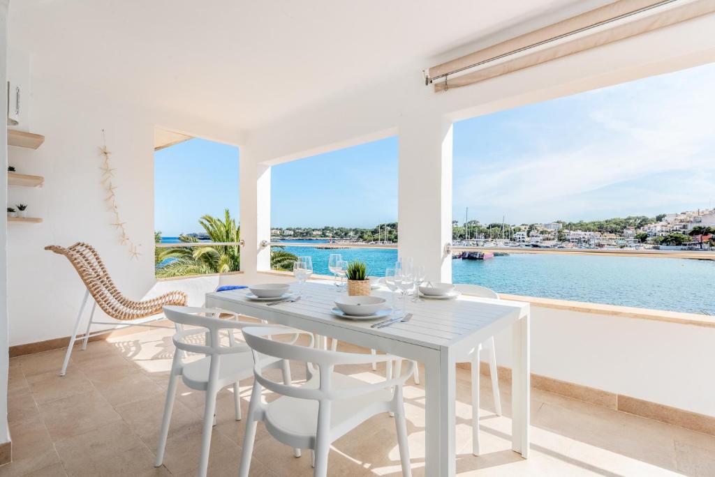 une salle à manger blanche avec vue sur l'eau dans l'établissement Apartment Sa Caseta 2 by Mallorca House Rent, à Portopetro