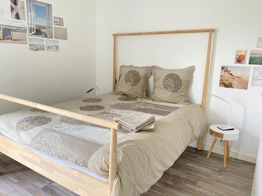 a bedroom with a bed with a wooden frame at Résidence des 3 îles, en plein centre-ville, à 5 min des plages, 3 appartements neufs in Étables-sur-Mer