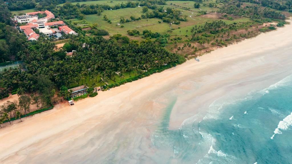 eine Luftblick auf einen Strand mit Häusern und das Meer in der Unterkunft Planet Hollywood Beach Resort Goa in Utorda
