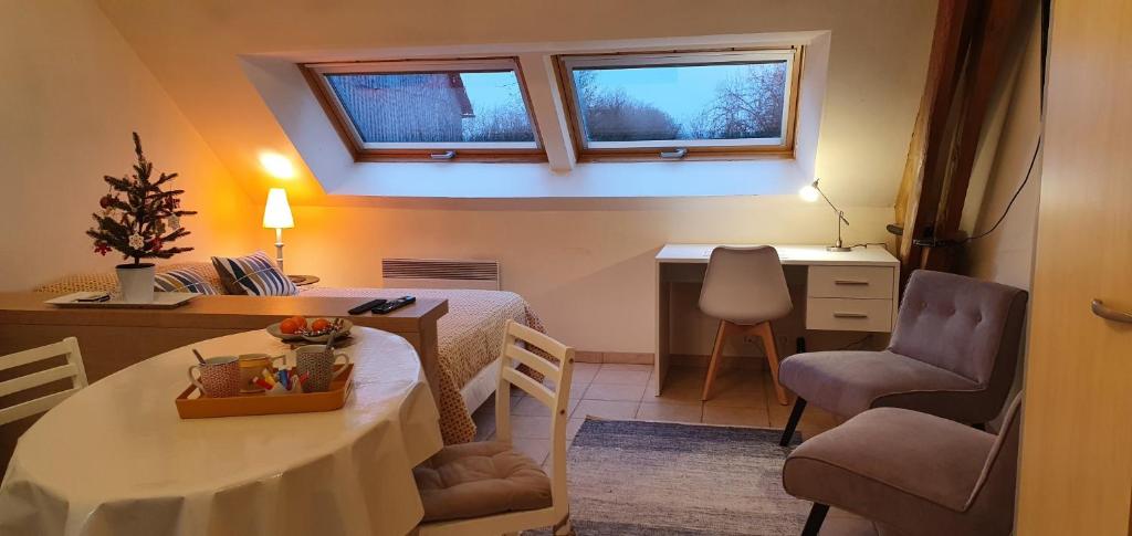 a small room with a table and a desk with two windows at La Hulotte in Villers-Carbonnel