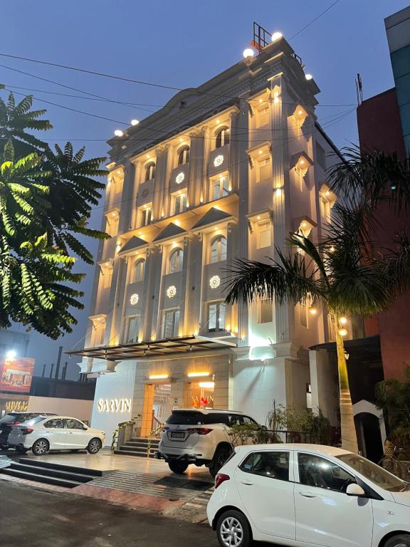 Hotel Sarvin في لاكناو: مبنى فيه سيارات تقف امامه