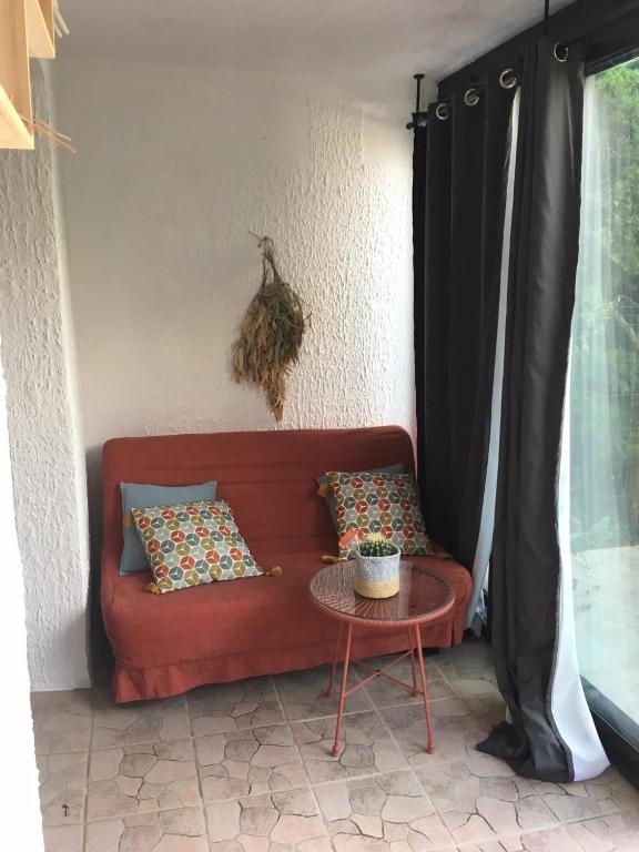 a red couch with pillows sitting next to a table at T2 à 2 minutes de la plage in La Londe-les-Maures